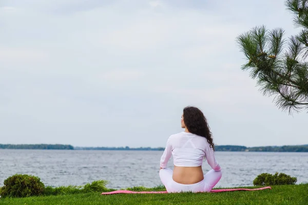 Pregnant woman is practicing yoga beside river — Stock Photo, Image