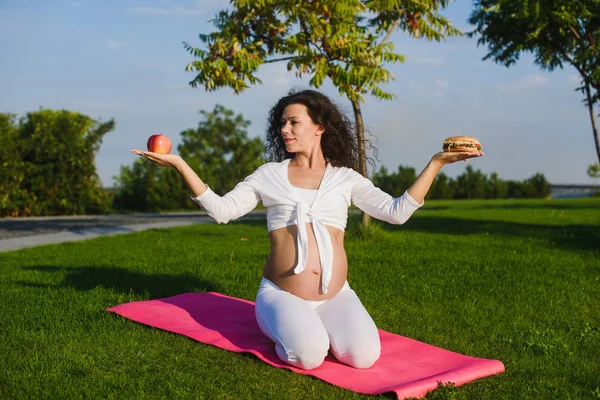 Femeia care alege între un hamburger și un măr . — Fotografie, imagine de stoc