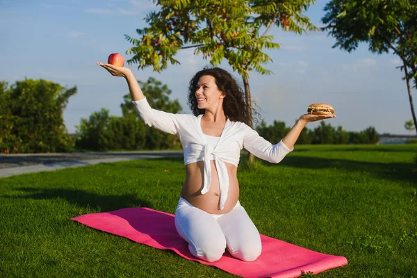 Femeia care alege între un hamburger și un măr . — Fotografie, imagine de stoc