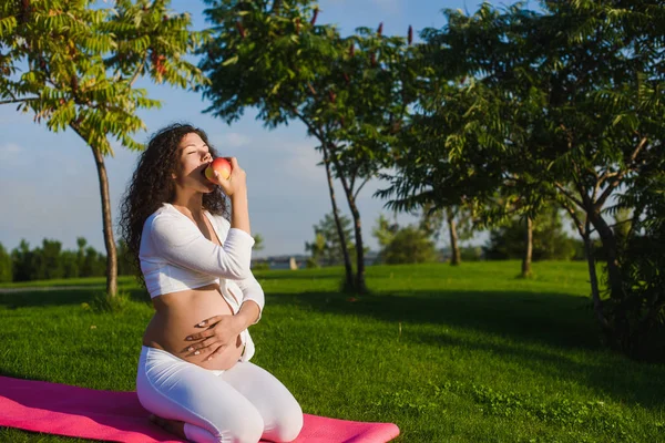 Belle femme enceinte avec une pomme dans le parc . — Photo
