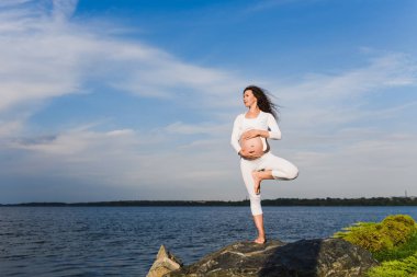 Yoga ağaç poz pregnat kadın tarafından.