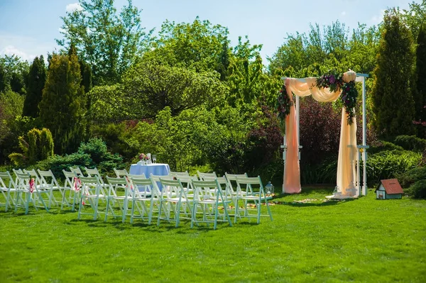 Arco de boda y sillas blancas en el jardín — Foto de Stock