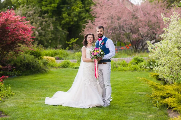 Νύφη και ο γαμπρός που θέτουν σε όμορφο κήπο — Φωτογραφία Αρχείου