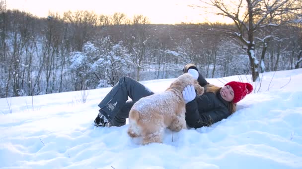 女孩躺在雪地上, 拥抱她的狗 — 图库视频影像
