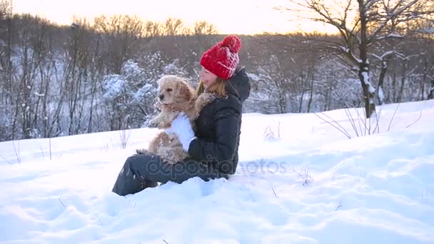 Mujer joven sentada con su perro en la nieve al aire libre — Vídeos de Stock