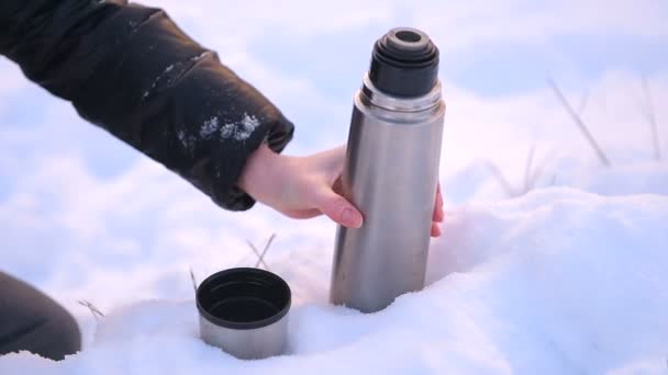 Metallthermoskanne aus nächster Nähe mit weiblicher Hand im Schnee — Stockvideo