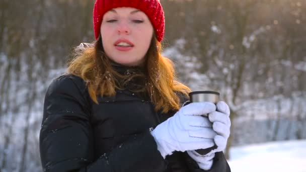 Chica en sombrero rojo beber té en el bosque congelado — Vídeos de Stock