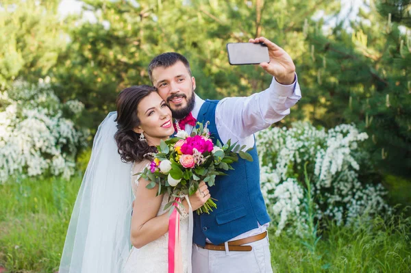 Groom fazer foto com sua noiva ao ar livre — Fotografia de Stock