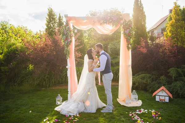 Casal feliz beijando sob o arco têxtil — Fotografia de Stock