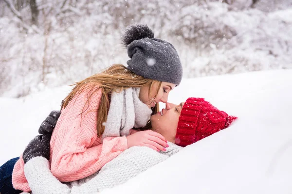 Lyckliga paret låg ner och kysser i snö — Stockfoto