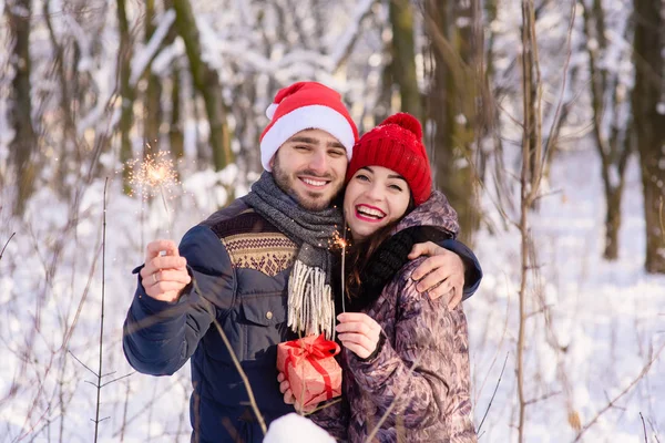 Lyckligt par poserar med röda hattar, bengaler på winter park — Stockfoto