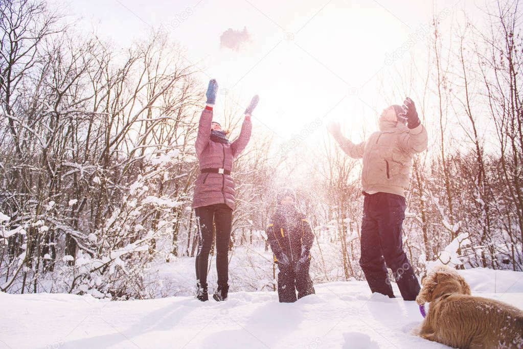 Happy family throw snow at sunset in winter forest