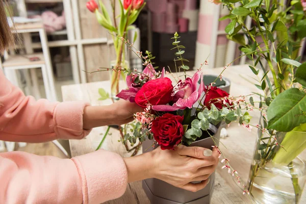 Female hands make bouquet at flower shop.