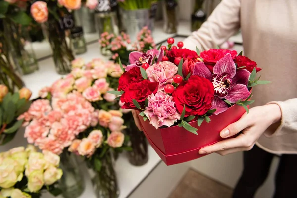 Kvinnliga händer håll röd ruta med blommor — Stockfoto