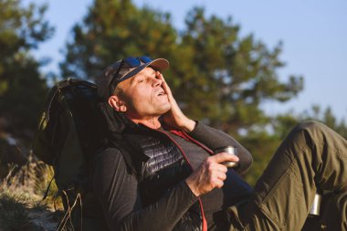 Yorgun turist sırt çantası ve fincanla oturur