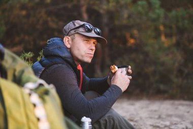 Erkek yürüyüşçü dışarıda yemek ve içmek için mola veriyor.