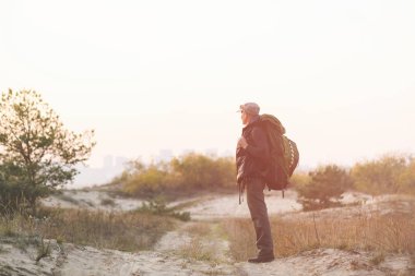 Büyük yeşil sırt çantalı turist uzaklara bakıyor.