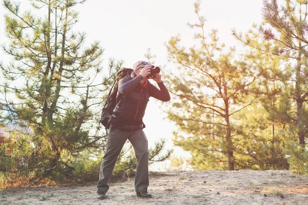 Senior man taking photo by camera in forest