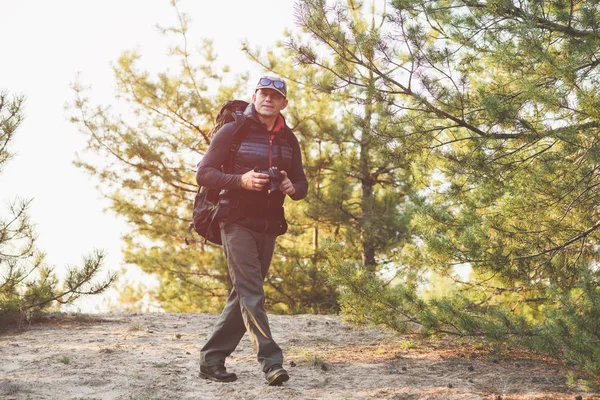 Senior man fotograferar med kamera i skogen — Stockfoto