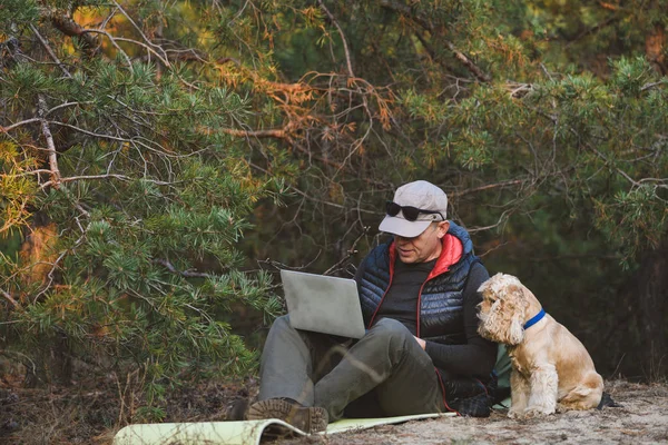 Människa och hund tittar på bärbar dator utomhus — Stockfoto