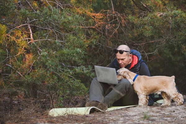 Man and dog watching Laptop computer outdoors