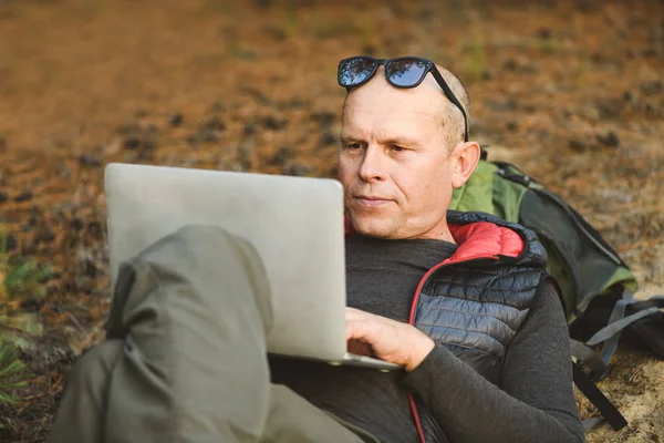 Backpacker turist ligger på matta med bärbar dator — Stockfoto