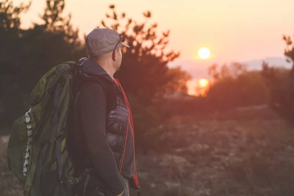 Man med ryggsäck titta på vacker solnedgång — Stockfoto