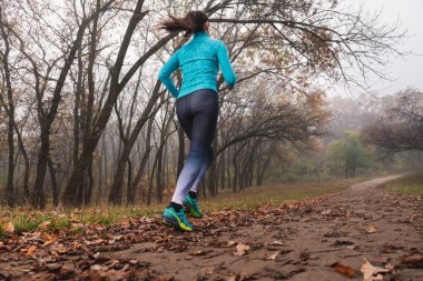 Sportif kadın parkta arkadan koşuyor.