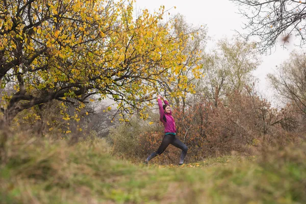 Flicka sträcker upp på hösten skog utomhus — Stockfoto