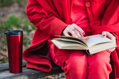 Kadın elleri açık kitap ve termosla