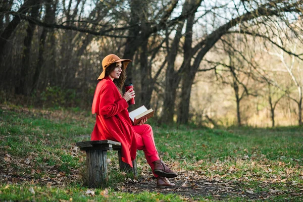 Mooie vrouw met boek en thermoskan buiten — Stockfoto