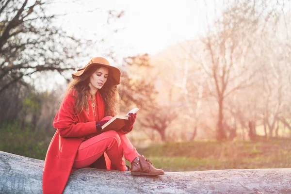 Meisje zit op logboek en lees boek — Stockfoto