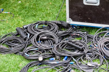 Many coiled black electric wires at grass clipart