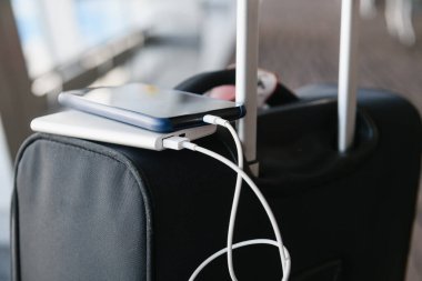 Valizin üzerindeki elektrik bankasından akıllı telefon şarj ediliyor.