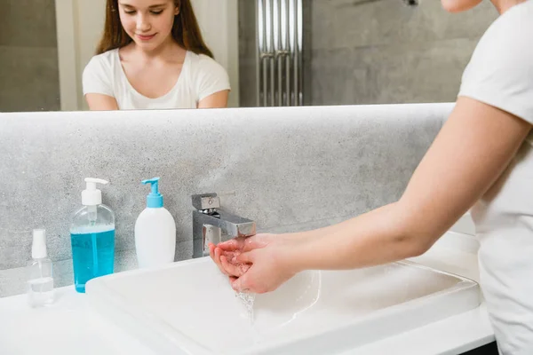 浴室の若い女性バスルームで白と青のプラスチックボトルに液体石鹸で手と腕を洗う 儀式衛生 ウイルス保護コンセプト — ストック写真