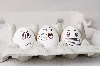 Komik duygusal yüzlü beyaz yumurtalar tarafından boyanmış. Salgın sırasında bahar tatili için kağıt tepsiye kapatılmış..