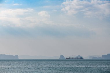 Gün batımında deniz yaşamının manzarası, ufukta kayalar, gemiler ve balıkçılar.