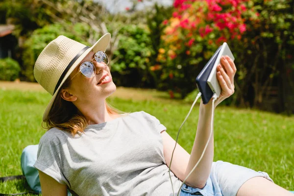 Happy woman with electronics outdoors charge phone