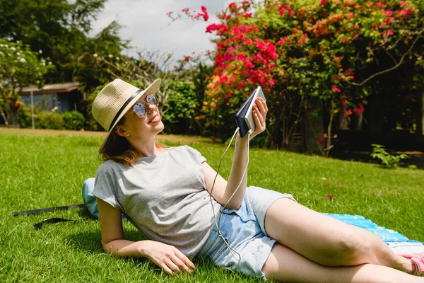 Glimlachende Jonge Vrouw Lag Groen Gras Onder Zomerzon Houd Smartphone — Stockfoto