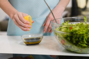 Kadın salata sosuna limon suyu sıkıyor.