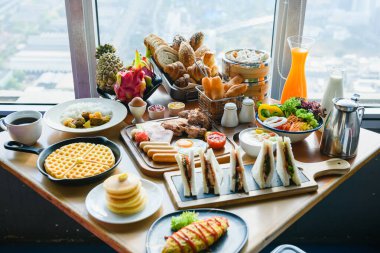 Kıtasal rüya kahvaltılı masa - meyveler, yumurtalar, sandviçler, salata, fırın, pencerenin önünde sıcak ve soğuk içecekler