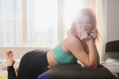 Spor kıyafetleri giyen bir kız, dünya virüs izolasyonu sırasında evdeki spor antrenmanlarından sonra kanepede yatıyordu.