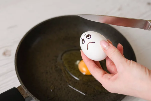 Crack white egg with sad painted face