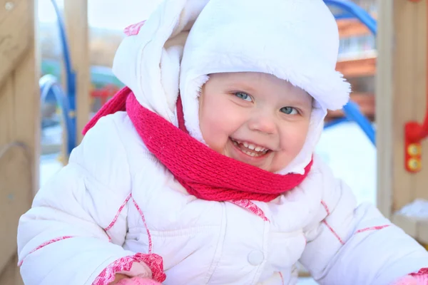 Happy little girl in white plays on playground and smiles — Stock Photo, Image