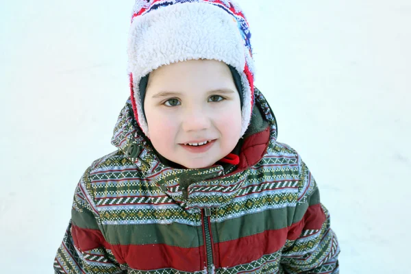 Feliz menino bonito olha para a câmera no dia ensolarado de inverno — Fotografia de Stock