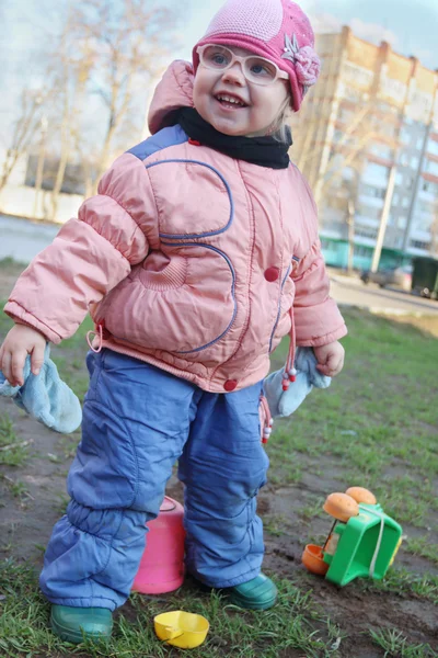 Счастливая маленькая девочка в поддельных очках играет с пластиковыми игрушками — стоковое фото