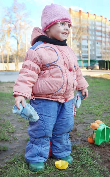Gelukkig klein meisje in nep bril staat onder plastic speelgoed — Stockfoto