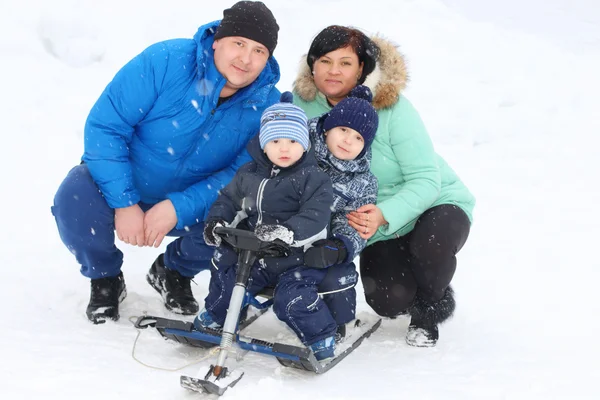 Счастливая семья (отец, мать, двое сыновей) позирует со снегоходом — стоковое фото