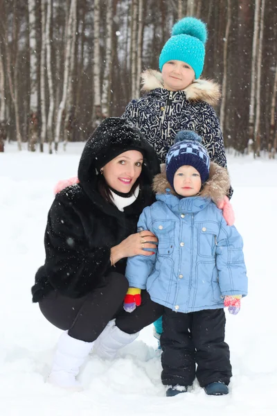 Szczęśliwa matka z synem, Córka w zimowy dzień podczas opadów śniegu — Zdjęcie stockowe