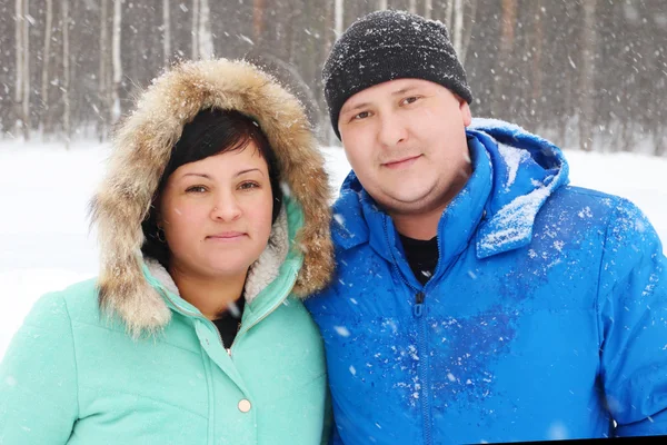Felice coppia grassa guarda la fotocamera nel parco durante la nevicata — Foto Stock